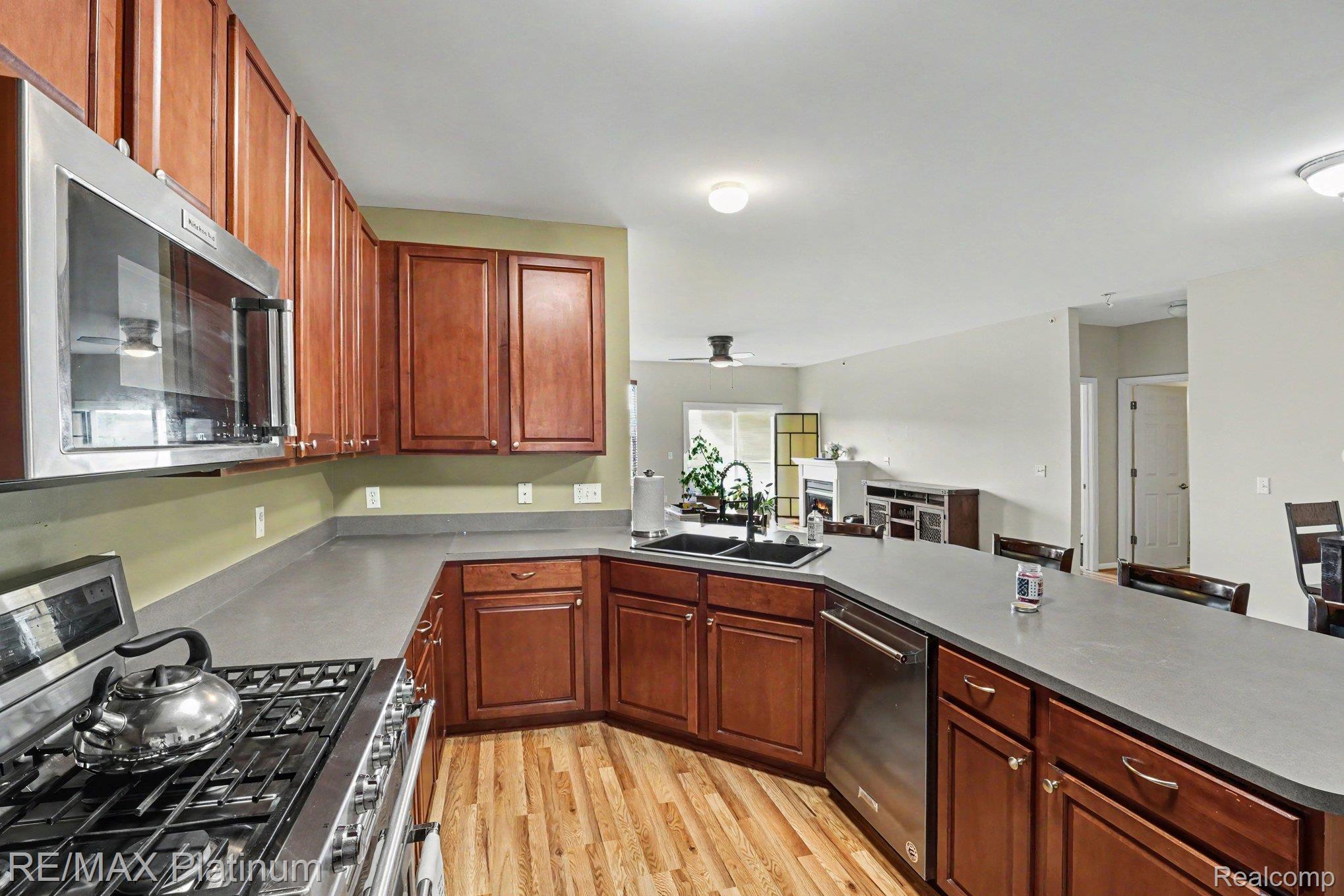 10217 Crossview Trail Howell, MI 48855 - Photo 13 of 26 Kitchen featuring wood-finish flooring, cherry wood cabinetry, stainless steel appliances, and solid surface countertops