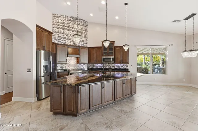 a kitchen with stainless steel appliances kitchen island granite countertop a refrigerator a stove top oven and a sink