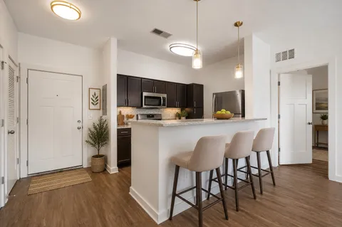a kitchen with stainless steel appliances a dining table chairs refrigerator microwave and cabinets