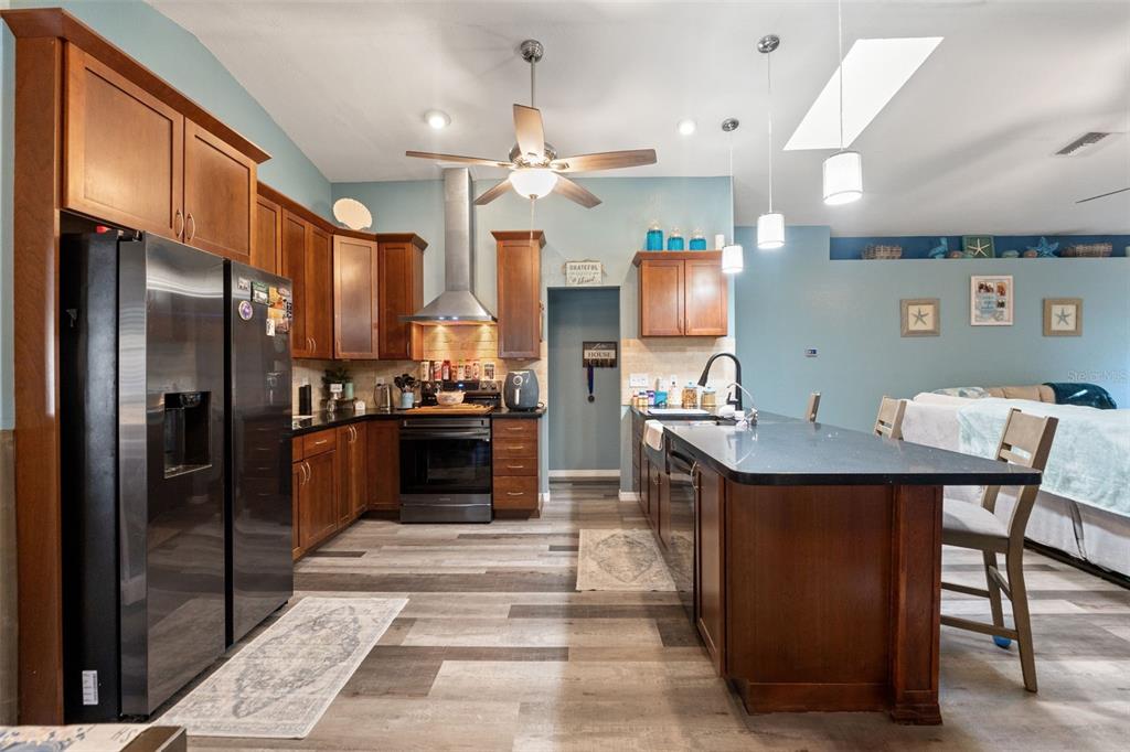 7180 Royal Oak Drive Spring Hill, FL 34607 - Photo 13 of 42 a kitchen with stainless steel appliances kitchen island granite countertop a refrigerator a stove a sink and a dining table with wooden floor