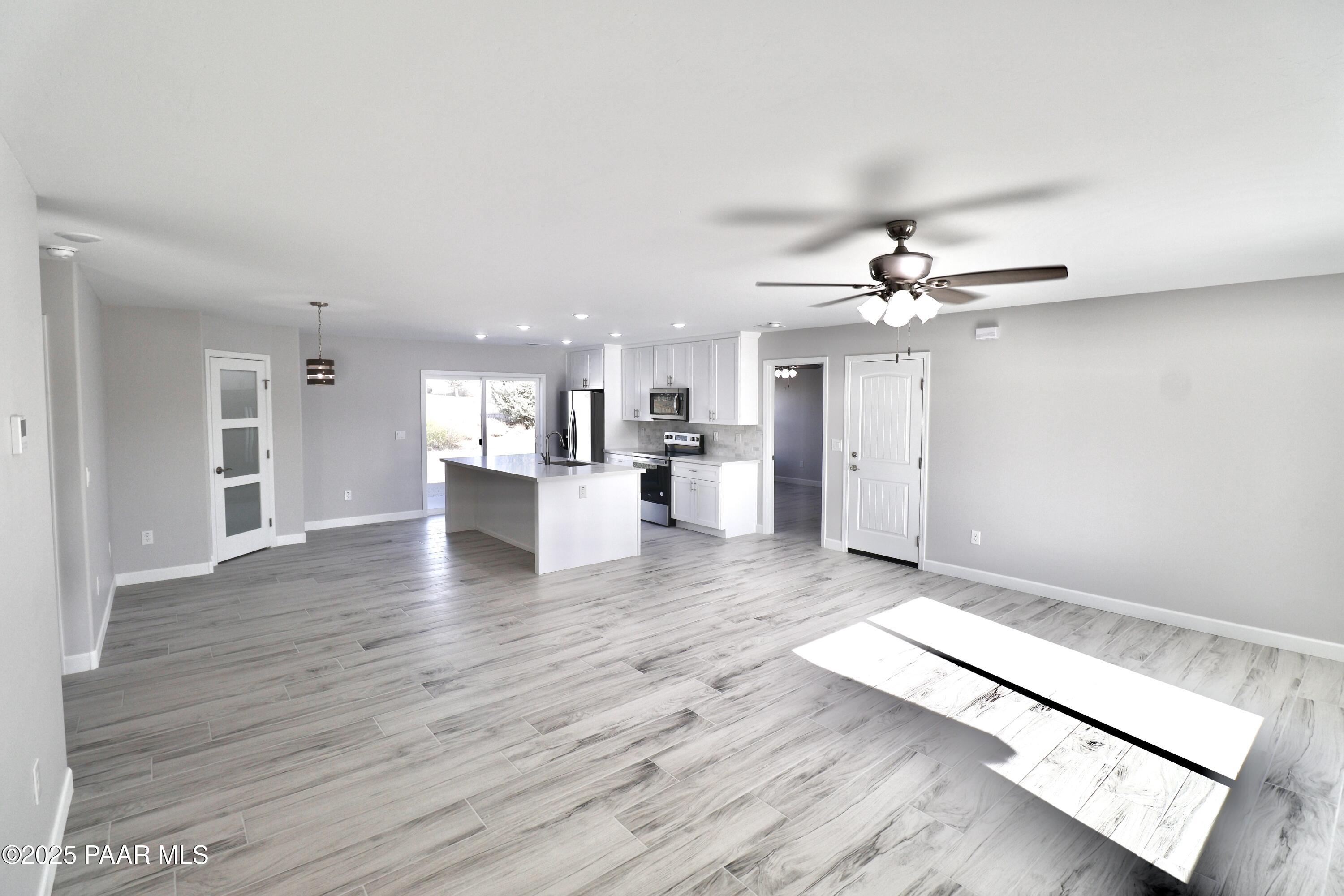 20182 East Mesa Verde Road Mayer, AZ 86333 - Photo 3 of 17 a view of an empty room with wooden floor and a kitchen