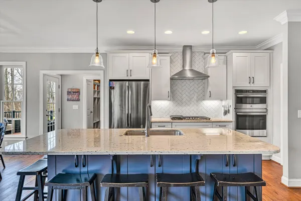 a kitchen with stainless steel appliances kitchen island a table chairs in it and wooden floors