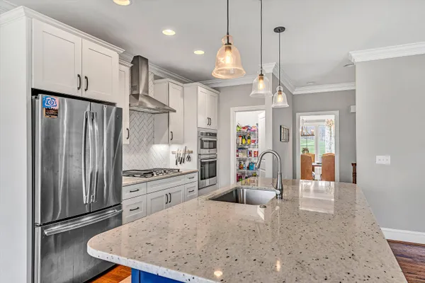 a kitchen with stainless steel appliances granite countertop a refrigerator a oven and a sink