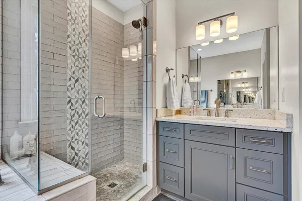 a bathroom with a granite countertop sink a mirror and shower