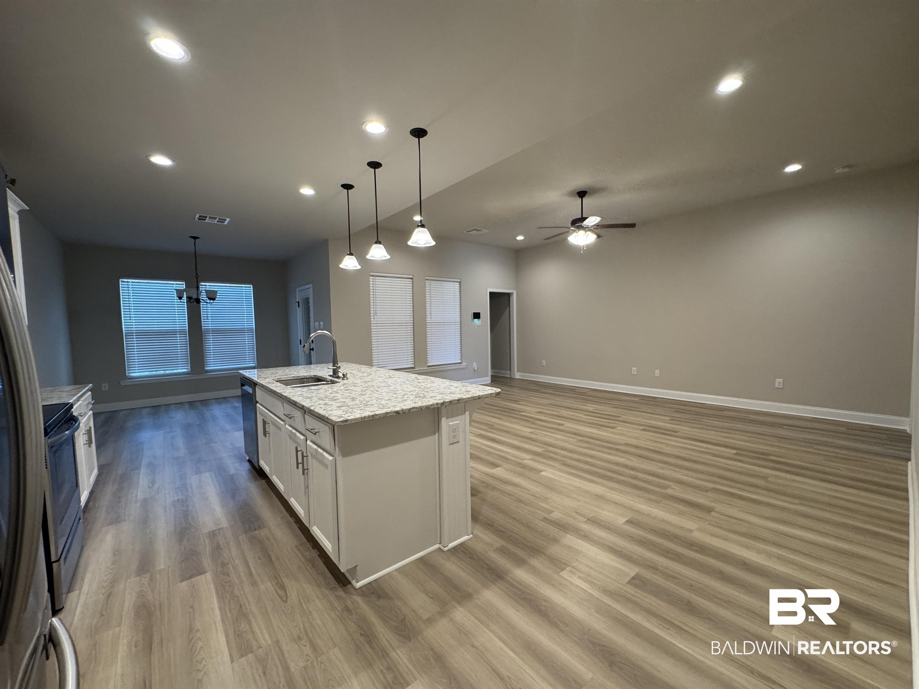 1060 Chloe Street Foley, AL 36535 - Photo 14 of 28 Open-concept living area featuring a kitchen island with stone-finish countertop, light wood-finish flooring, recessed lighting, and a ceiling fan