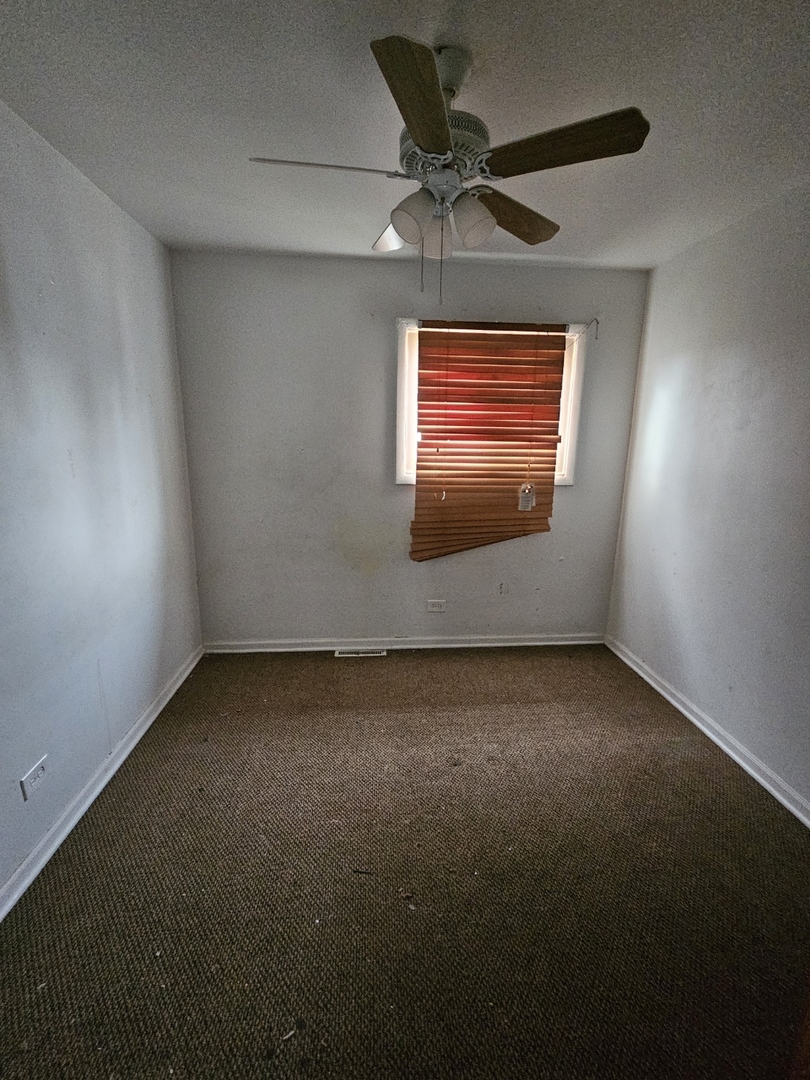 2105 171st Street Hazel Crest, IL 60429 - Photo 6 of 11 an empty room with a ceiling fan and a window
