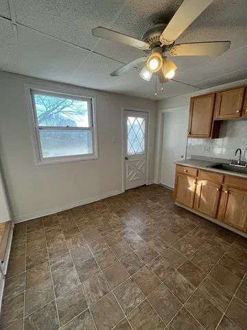 a view of a livingroom with kitchen furniture and a ceiling fan