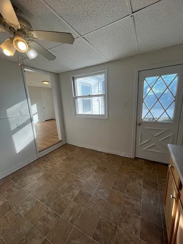 a view of an empty room with wooden floor and fan