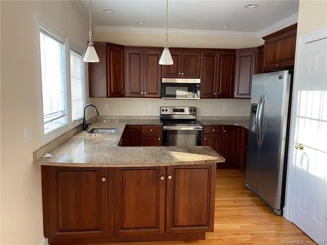 a kitchen with stainless steel appliances granite countertop a sink a stove a refrigerator and cabinets