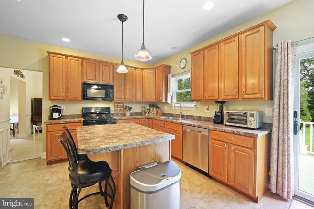 a kitchen with kitchen island granite countertop a stove a sink a oven a dining table and chairs with wooden floor