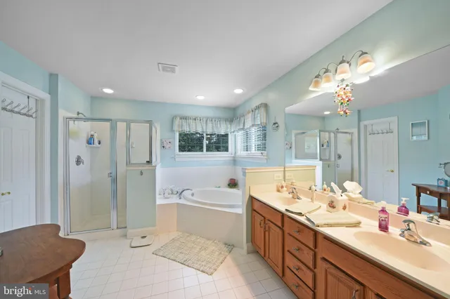 a bathroom with a tub a double vanity sink a window and a mirror