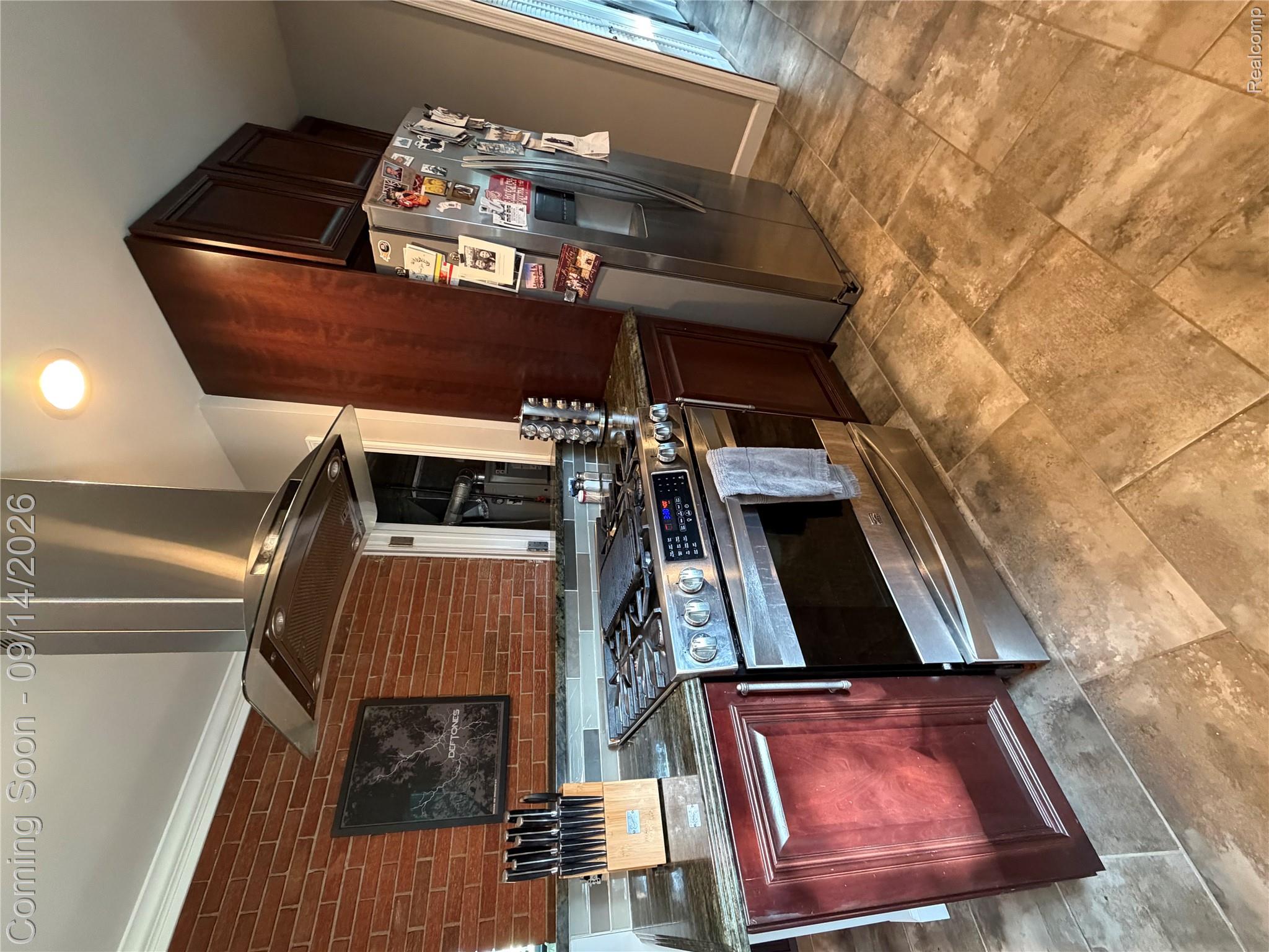 1615 Ladd Road Walled Lake, MI 48390 - Photo 11 of 28 Stainless steel appliances, brick-patterned wall, dark wood-finish cabinetry, tile flooring, and granite countertops