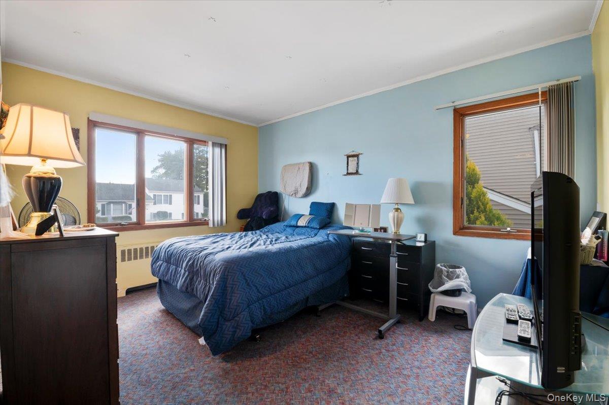 26 Bradford Lane Bethpage, NY 11714 - Photo 9 of 24 a bedroom with a bed and a flat tv screen on the dresser