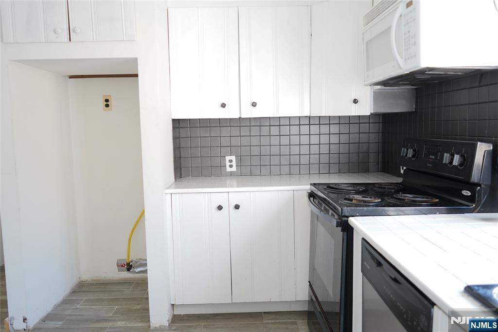 83 Roosevelt Avenue Butler, NJ 07405 - Photo 16 of 32 a kitchen with granite countertop white cabinets and white appliances