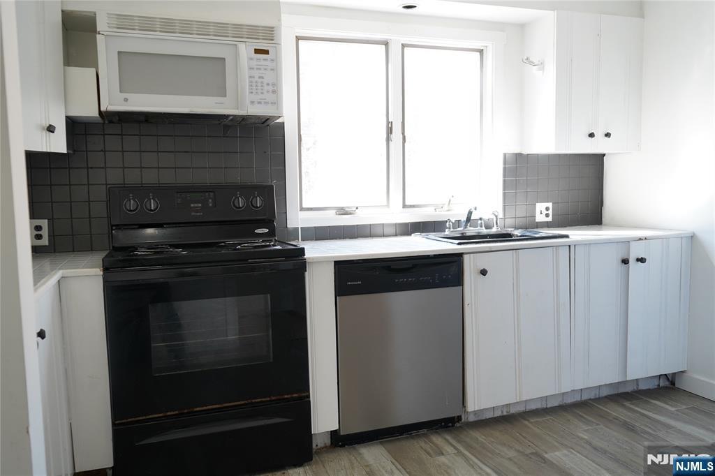 83 Roosevelt Avenue Butler, NJ 07405 - Photo 18 of 32 a kitchen with stainless steel appliances a stove sink and cabinets