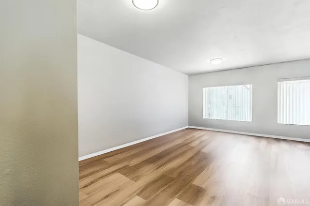 a view of an empty room with wooden floor and a window