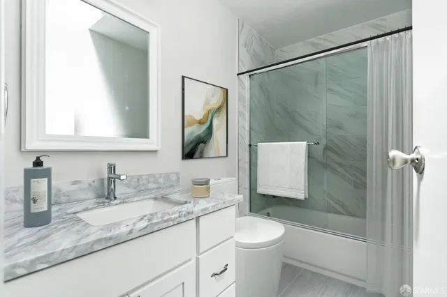 a bathroom with a granite countertop sink toilet and shower