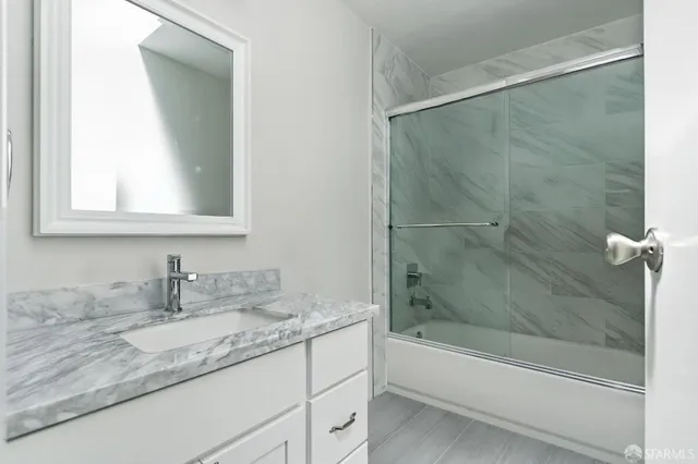 a bathroom with a granite countertop sink a mirror and a bathtub