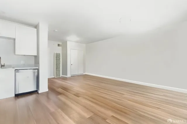 a view of a kitchen with a sink and dishwasher a refrigerator with white cabinets