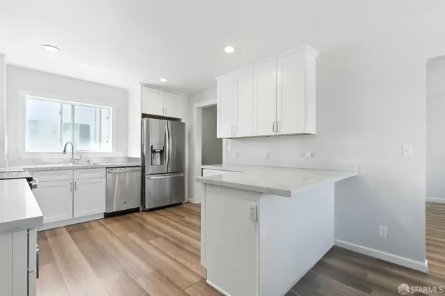 a kitchen with granite countertop a sink stove refrigerator and cabinets