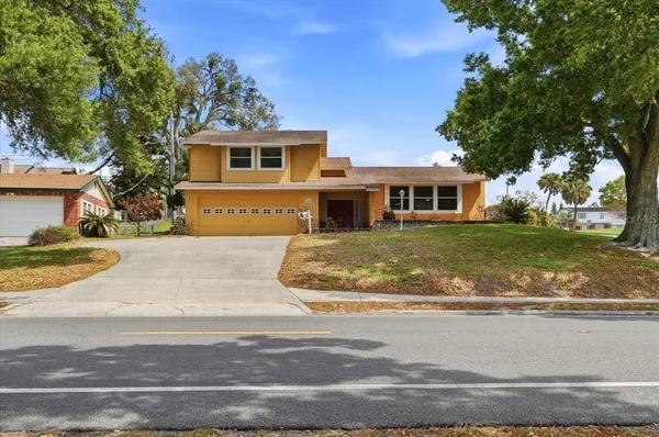 a view of a white house next to a yard with big trees