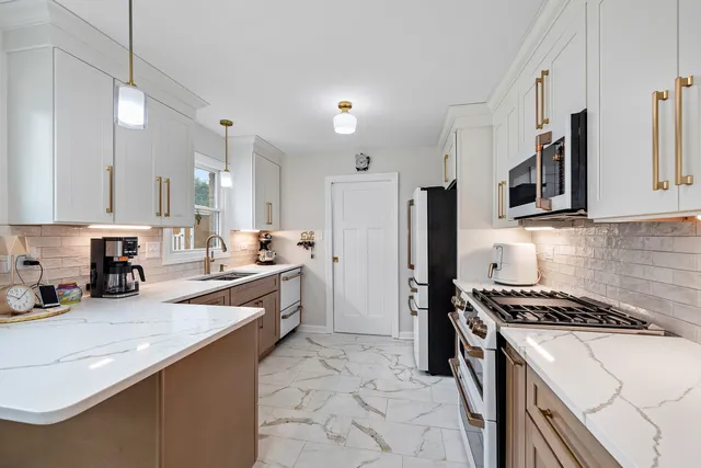 a kitchen with stainless steel appliances a sink a stove a refrigerator cabinets and a counter top space