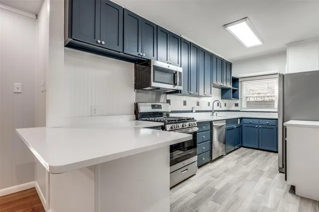 a kitchen with stainless steel appliances a sink a stove a refrigerator cabinets and a window