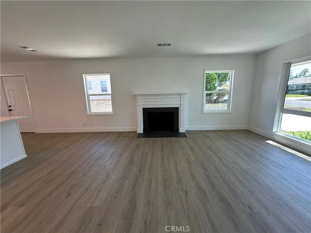 an empty room with wooden floor windows and fireplace