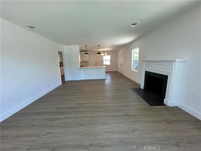 a view of empty room with wooden floor and fireplace