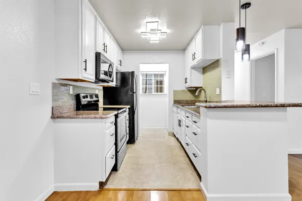 a kitchen with stainless steel appliances granite countertop a refrigerator a stove and a sink