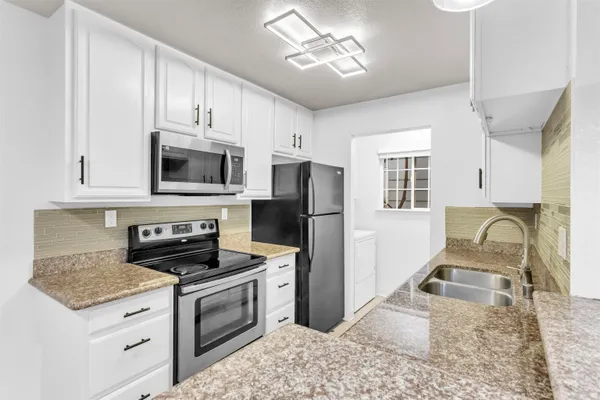 a kitchen with granite countertop a stove a sink and a microwave
