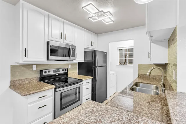 a kitchen with granite countertop a stove a sink and a microwave