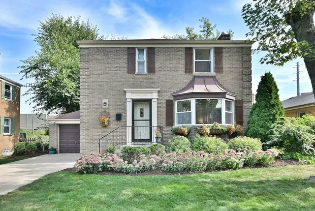 a front view of a house with a yard and potted plants