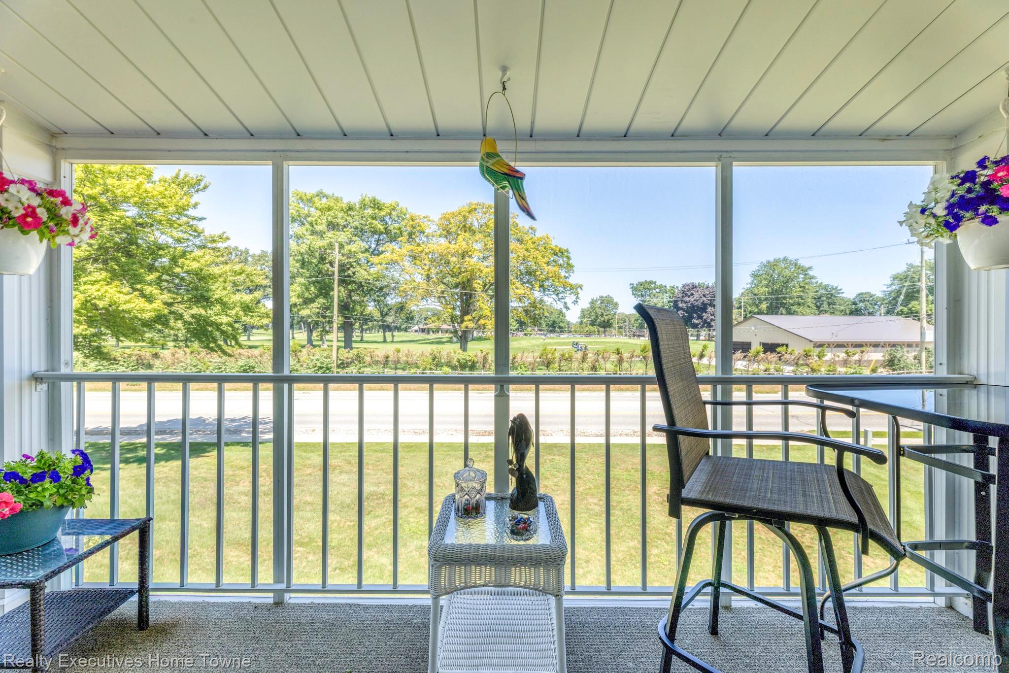 1467 Krafft Road, Unit 8 Port Huron, MI 48060 - Photo 3 of 30 Screened porch featuring a textured floor, slatted ceiling, and an expansive outdoor backdrop of mature trees and green space