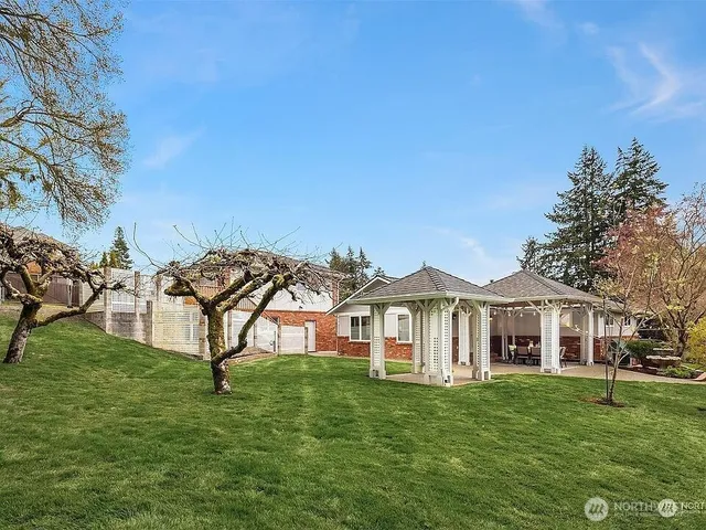 a view of a white house with a big yard and large trees
