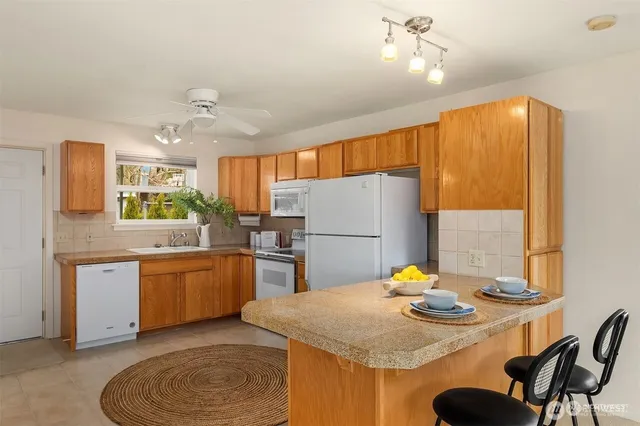 a kitchen with stainless steel appliances granite countertop a sink dishwasher and a refrigerator with wooden floor
