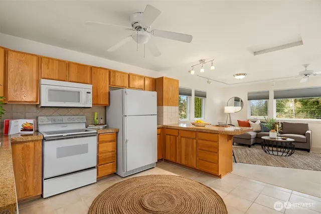 a kitchen with stainless steel appliances granite countertop a refrigerator a sink dishwasher a dining table and chairs with the outer view