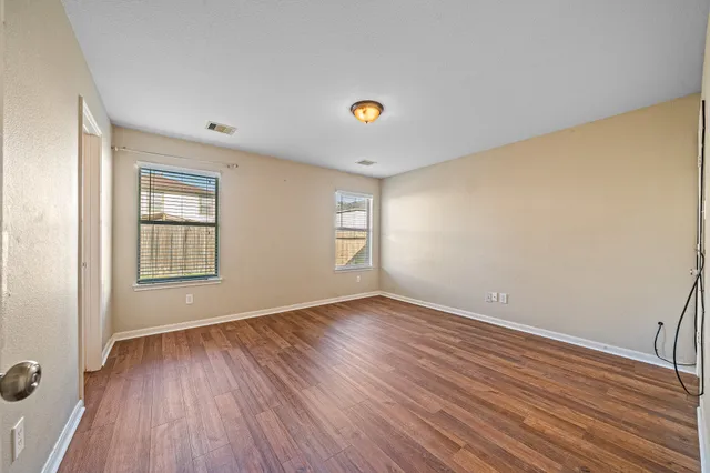 a view of an empty room with window and wooden floor