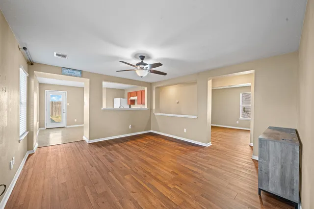 a view of an empty room with wooden floor and a window
