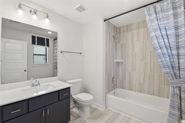 a bathroom with a bathtub shower sink vanity mirror and toilet