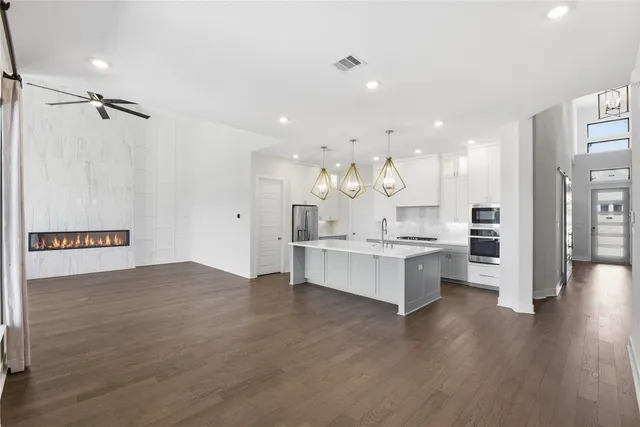 a large kitchen with stainless steel appliances kitchen island a large counter top and a wooden floors