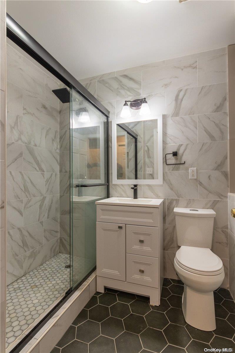 334 Lincoln Road Brooklyn, NY 11225 - Photo 3 of 11 a bathroom with a granite countertop sink toilet a mirror and shower