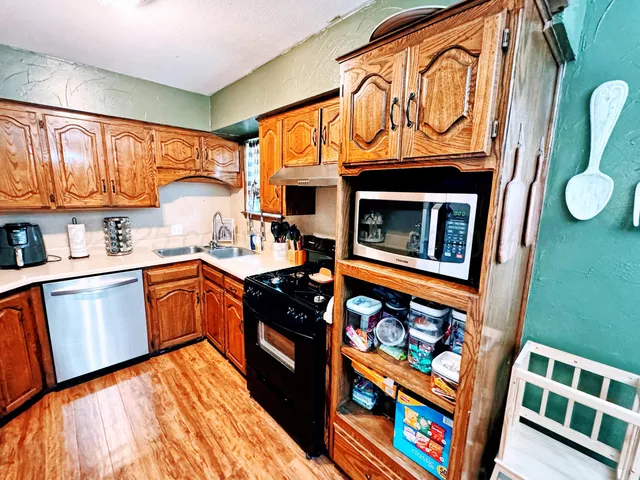 a kitchen with stainless steel appliances granite countertop a stove a sink and a microwave