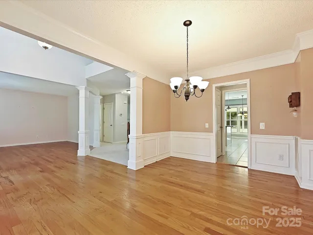 a view of a big room with wooden floor chandelier and windows