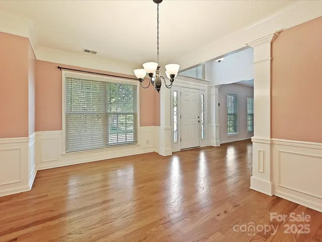 a view of a livingroom with wooden floor staircase and a kitchen space