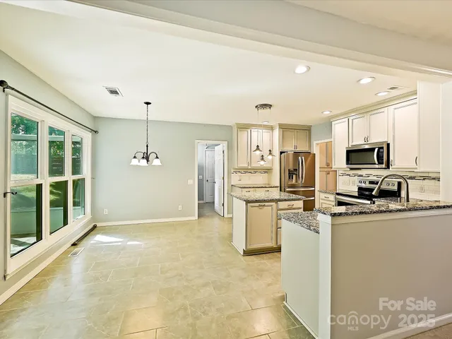 a kitchen with kitchen island granite countertop stainless steel appliances a stove a sink and a refrigerator