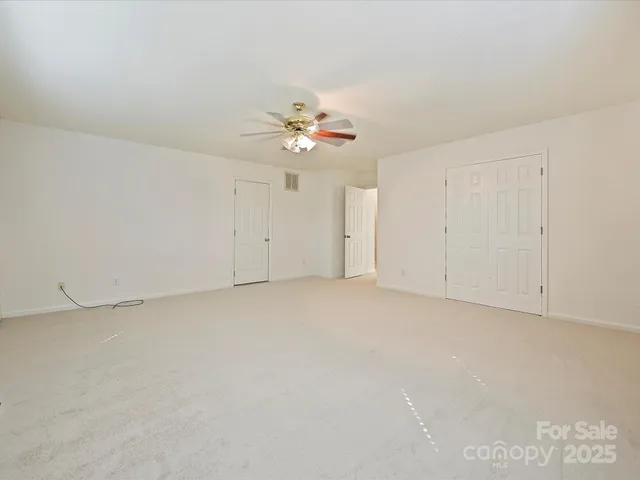 an empty room with windows and ceiling fan