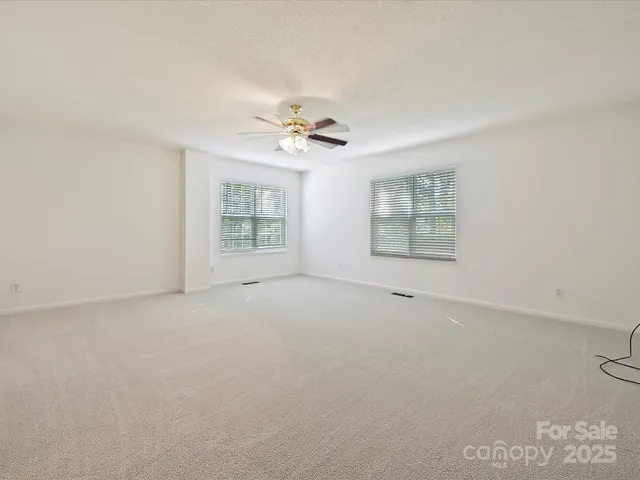 an empty room with a window and a ceiling fan