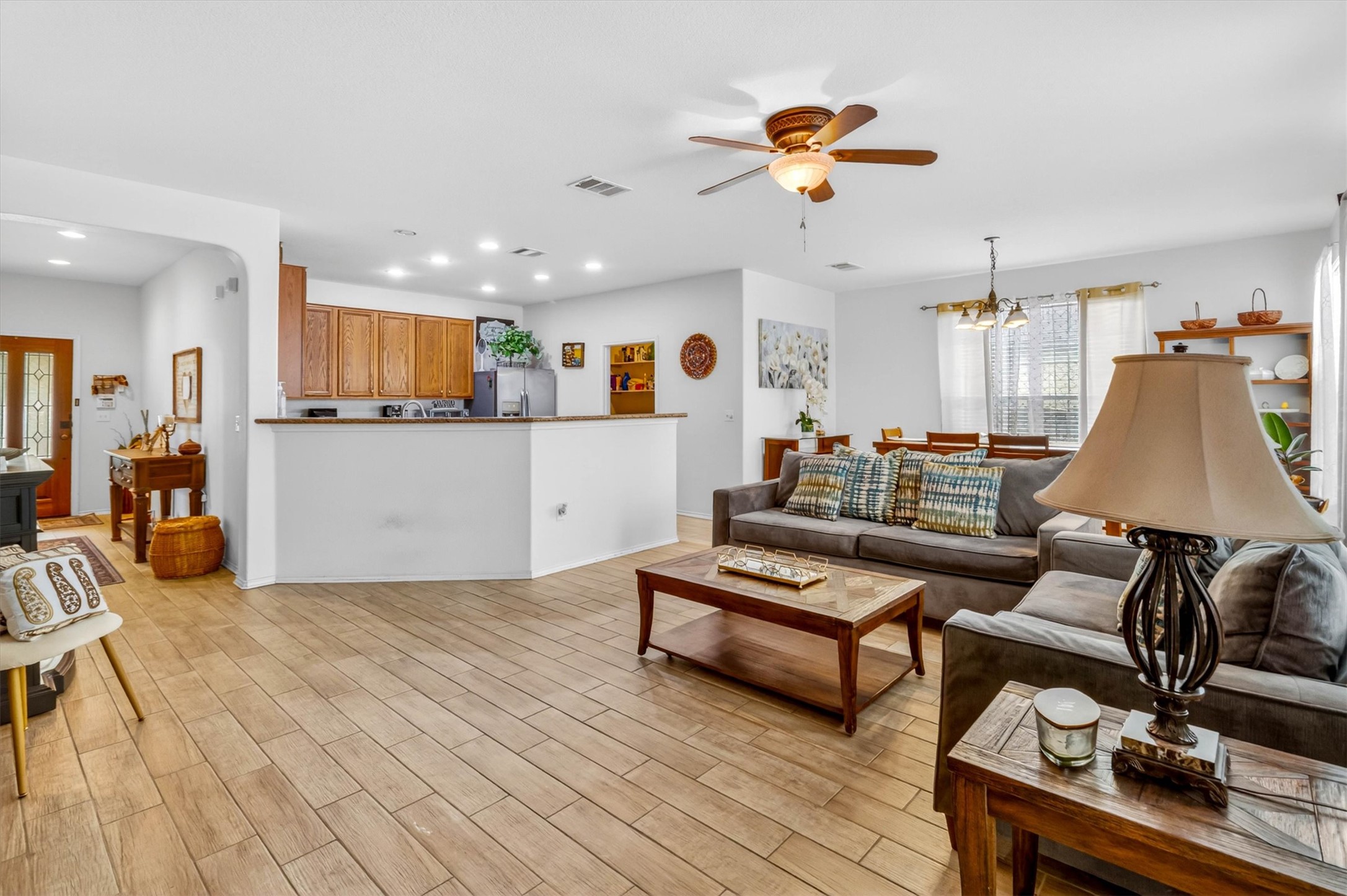 460 Waterleaf Boulevard Kyle, TX 78640 - Photo 7 of 30 An inviting open-concept living space features light wood-look flooring, a kitchen with recessed lighting, and a well-lit dining area.