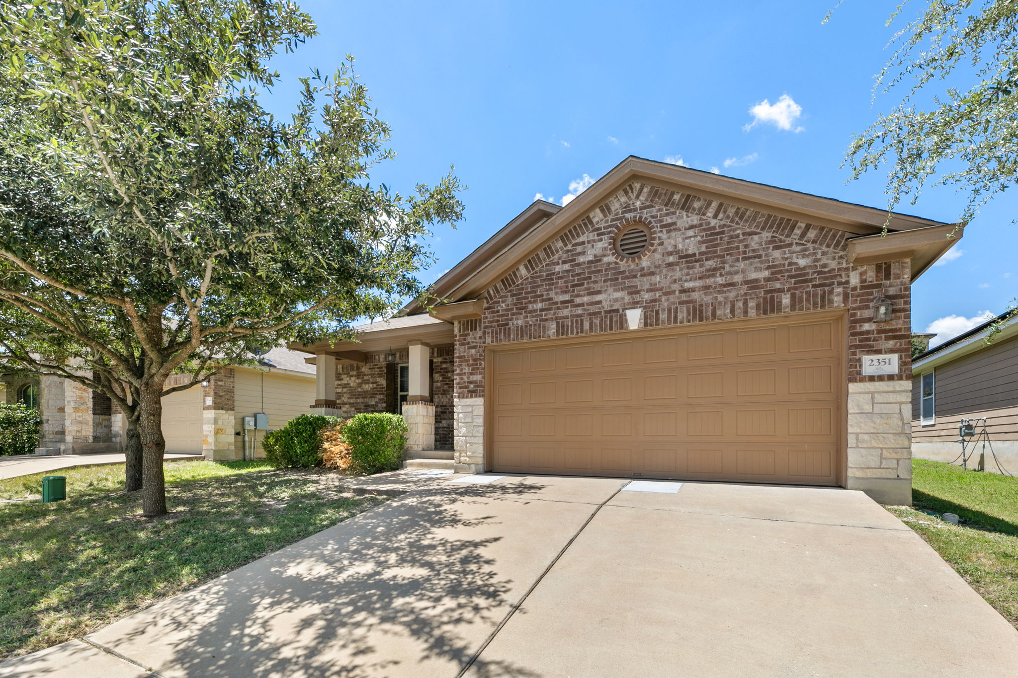 2351 Intrepid Drive Buda, TX 78610 - Photo 1 of 1 View of front of house featuring a garage, brick siding, driveway, and a front lawn